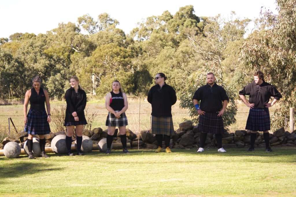 Strong men and women dressed in kilts waiting in line for competition to start